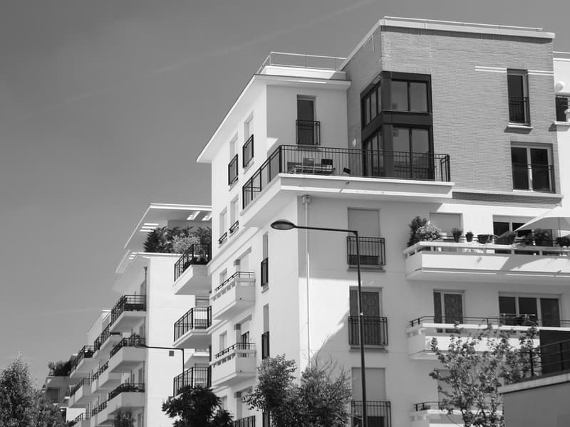 Immeubles résidentiels modernes avec balcons fleuris et terrasses ensoleillées.