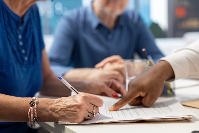 Gros plan sur des mains signant des documents lors d'une réunion, illustrant la cession d'un cabinet d'expertise comptable.