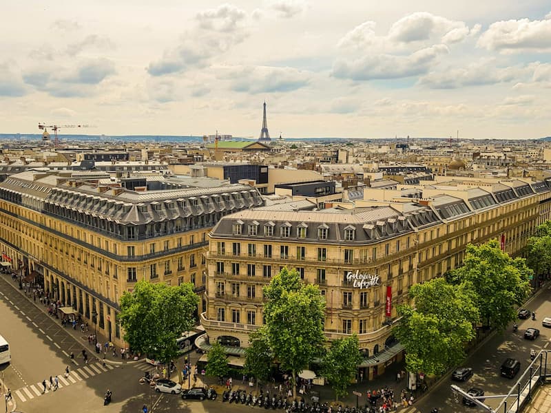 Vue aérienne des Galeries Lafayette Haussmann avec la Tour Eiffel en arrière-plan, architecture parisienne typique et toits mansardés