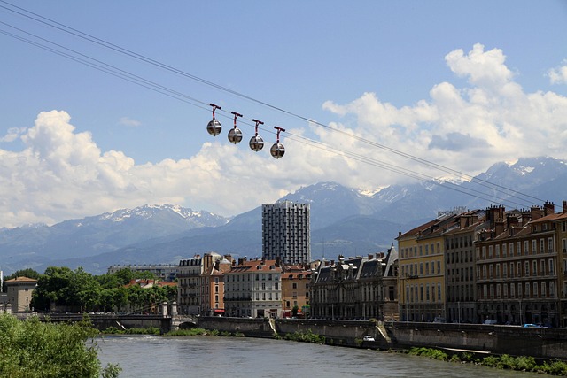 Téléphérique de Grenoble traversant l’Isère avec vue sur les Alpes et les toits colorés de la ville.