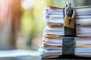 Pile de documents confidentiels attachés et sécurisés par un cadenas doré lors d'une cession de cabinet comptable